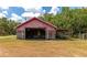 Rustic red barn with covered storage and wooden siding at 15440 County Road 675, Parrish, FL 34219