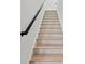 Staircase with wooden steps, white risers, and modern black handrail at 1805 Goldenrod St, Sarasota, FL 34239