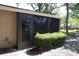 Screened porch exterior view with access door and landscaping at 1213 Tallywood Dr # 7007, Sarasota, FL 34237