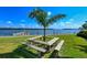 Waterfront picnic area with a wooden table and benches under a palm tree at 4350 Chatham Dr # E307, Longboat Key, FL 34228