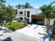 Modern home with white exterior, dark windows, wood-look accents, and a paved driveway, surrounded by lush landscaping at 2226 Grove St, Sarasota, FL 34239