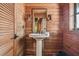 Bathroom with pedestal sink and wood-paneled walls at 7147 La Lenaire Dr, Longboat Key, FL 34228