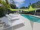 Inviting backyard pool area with lounge chairs, shade sail, and lush landscaping at 8010 Marina Dr, Holmes Beach, FL 34217