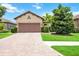 Tan house with brown garage door and a brick paver driveway at 10339 Highland Park Pl, Palmetto, FL 34221