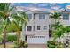 Tan three-story house with white garage door and palm trees at 219 81St St, Holmes Beach, FL 34217