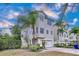 Three-story light beige home with a two-car garage and lush landscaping at 219 81St St, Holmes Beach, FL 34217