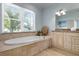 Bathroom featuring a large soaking tub, large window overlooking tropical foliage, double sink, and marble countertops at 4805 2Nd Ave, Holmes Beach, FL 34217