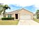 Tan single-story home with a two car garage, manicured lawn, and a palm tree at 7380 Mikasa Dr, Punta Gorda, FL 33950