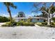 Charming light-blue home with a gravel yard, lush landscaping, and mature trees at 506 69Th St, Holmes Beach, FL 34217