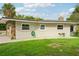 House exterior with stone accents, a green lawn and mature trees at 907 E Rosedale Rd, Venice, FL 34293
