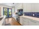 Modern kitchen with white cabinets, blue tile backsplash and stainless steel appliances at 108 Tern Dr, Anna Maria, FL 34216
