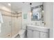 Modern bathroom with a glass shower, gray vanity, and decorative mirror at 108 Tern Dr, Anna Maria, FL 34216