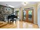 Sunlit living room with hardwood floors, stone wall, and a baby grand piano at 4714 Elder Berry Dr, Sarasota, FL 34241