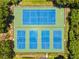 Overhead aerial view of two well-maintained tennis courts surrounded by lush landscape at 255 Sherwood Dr # 255U, Bradenton, FL 34210