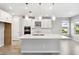 Modern kitchen with white cabinets, a large island, stainless steel appliances, and pendant lighting at 7016 Foxboro Way, Nokomis, FL 34275