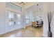 An elegant entryway with a light wood floor, a glass-paneled double door, and a view of the dining room at 8980 Artisan Way, Sarasota, FL 34240