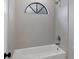 Clean bathroom with a bathtub and shower combination, and arched window at 4709 Foy Pl, Sarasota, FL 34243