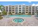 Community pool and hot tub providing a relaxing oasis for residents, surrounded by lush landscaping and multiple buildings at 1703 N Tamiami Trl # 302, Sarasota, FL 34234