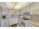 White kitchen with updated appliances and view into living area at 8911 Midnight Pass Rd # 410, Sarasota, FL 34242
