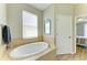 Oval soaking tub in a well-lit bathroom with a window and wood flooring at 350 River Enclave Ct, Bradenton, FL 34212
