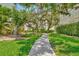 Brick pathway through a lush courtyard with large oak trees and green grass at 6157 Midnight Pass Rd # G11, Sarasota, FL 34242