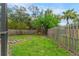 Fenced backyard featuring lush green grass, mature trees, and a swing set at 4175 Arrow Ln, Sarasota, FL 34232