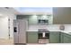 Well-lit kitchen featuring green cabinets, stainless steel appliances, and a stylish white backsplash at 4175 Arrow Ln, Sarasota, FL 34232