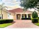 Lovely single-story home boasts a tile roof, brick driveway, covered front porch, and mature, manicured landscaping at 5901 Mariposa Ln, Sarasota, FL 34238