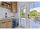 Modern wet bar with wine cooler, sink, and French doors to the patio at 301 Aurora E St, Venice, FL 34285