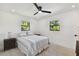 Well-lit bedroom with a ceiling fan, striped bedding, and two windows at 301 Aurora E St, Venice, FL 34285