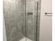 Contemporary shower with gray tiled walls, glass enclosure, and convenient inset shelving at 4860 Florida Rd, Venice, FL 34293