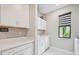 Bright laundry room with white cabinets, washer, dryer and a utility sink at 5244 Barnett Cir, Lakewood Ranch, FL 34211