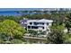 Contemporary waterfront home with sleek white facade, multiple balconies, and lush tropical landscaping at 1610 N Lodge Dr, Sarasota, FL 34239