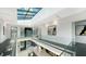 Modern hallway with glass elevator, skylight, and glass railing overlooking the foyer at 1610 N Lodge Dr, Sarasota, FL 34239