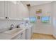 Laundry room with white cabinets, washer, dryer, and a sink at 5444 Gulf Of Mexico Dr, Longboat Key, FL 34228