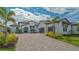 Expansive white home showcasing a paver driveway, two-car garage, tropical landscaping, and tile roof at 10629 Nicklaus Ct, Englewood, FL 34223