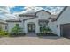 Charming white home exterior featuring a tile roof, arched entry, and professionally landscaped front yard at 10629 Nicklaus Ct, Englewood, FL 34223