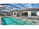 Backyard features screened-in pool, brick-paver patio, safety fence, and water view at 10629 Nicklaus Ct, Englewood, FL 34223