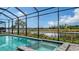 Screened-in pool with a spa and tranquil water view in lush backyard setting at 10629 Nicklaus Ct, Englewood, FL 34223