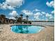 Community pool with lake view, surrounded by brick pavers, lounge chairs, and palm trees at 8930 Tuscany Isles Dr, Punta Gorda, FL 33950
