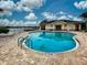 Community pool with lake view, surrounded by brick pavers, lounge chairs, and a cabana at 8930 Tuscany Isles Dr, Punta Gorda, FL 33950
