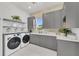 Well-appointed laundry room, featuring gray cabinetry, white counters, and built-in shelving at 11414 Brightly Dr, Venice, FL 34293