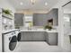 Modern laundry room with gray cabinets, quartz countertops, and high-end appliances at 11414 Brightly Dr, Venice, FL 34293