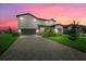 Two-story house with gray siding, gray paved driveway, and landscaping at sunset at 15425 White Linen Dr, Bradenton, FL 34211