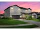 Two-story house with gray siding, gray paved driveway, and landscaping at sunset at 15425 White Linen Dr, Bradenton, FL 34211