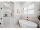 Bright bathroom with soaking tub, shuttered windows, and doorway access to a large walk-in closet at 1783 Bayview Dr, Sarasota, FL 34239