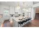 Bright, white kitchen with a marble island, pendant lighting, stainless steel appliances, and hardwood flooring at 1783 Bayview Dr, Sarasota, FL 34239