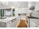 Bright kitchen features white cabinets, marble counters, stainless steel appliances and large windows at 1783 Bayview Dr, Sarasota, FL 34239