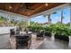 Inviting covered patio features tile flooring, wooden ceiling, comfortable seating, and lush tropical landscaping at 1783 Bayview Dr, Sarasota, FL 34239