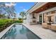 Backyard with a modern pool, an outdoor kitchen, a covered dining area, and mature tropical landscaping at 1783 Bayview Dr, Sarasota, FL 34239